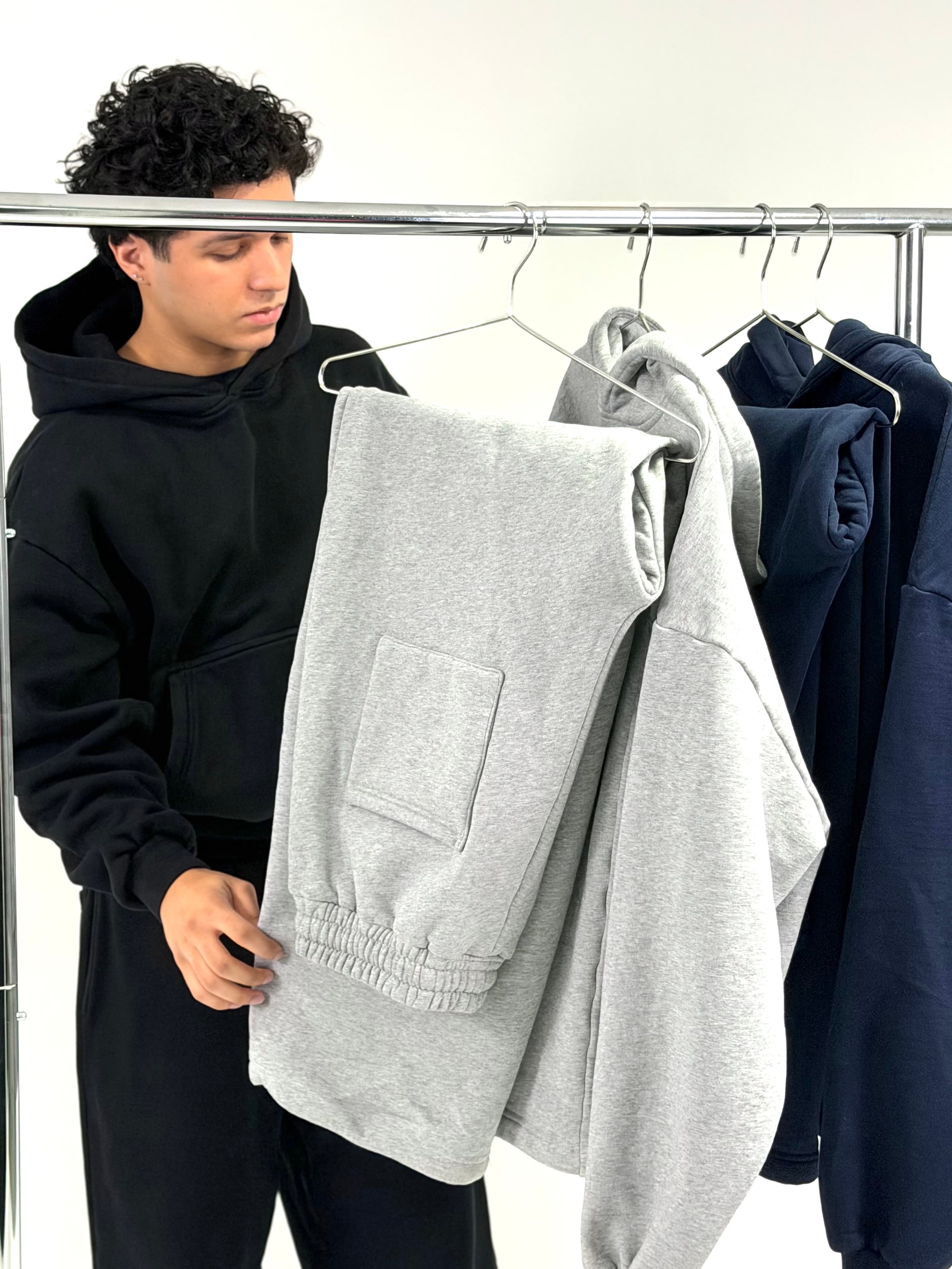 Model holding a grey VadaWear hoodie off the rack