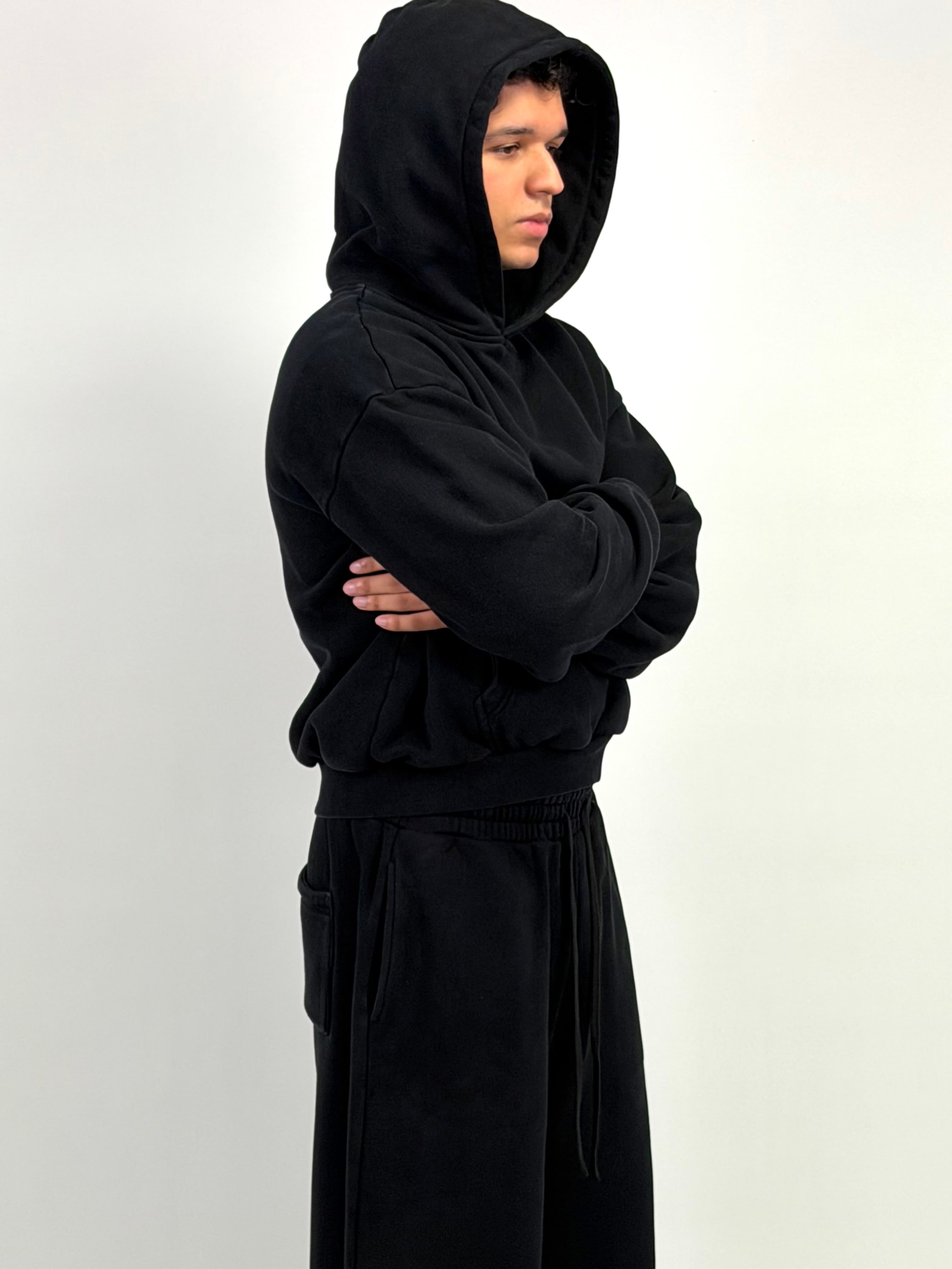 Model wearing a black VadaWear hoodie, arms crossed
